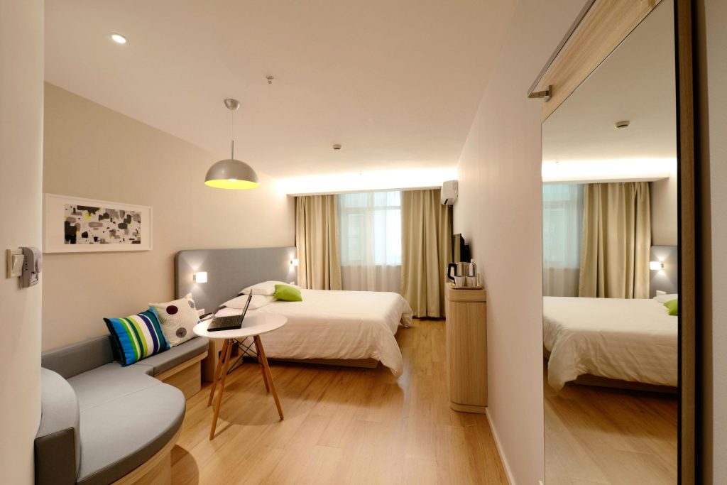Amplia habitación de hotel de estilo moderno con una decoración acogedora y tonos neutros, con mucha luz natural.